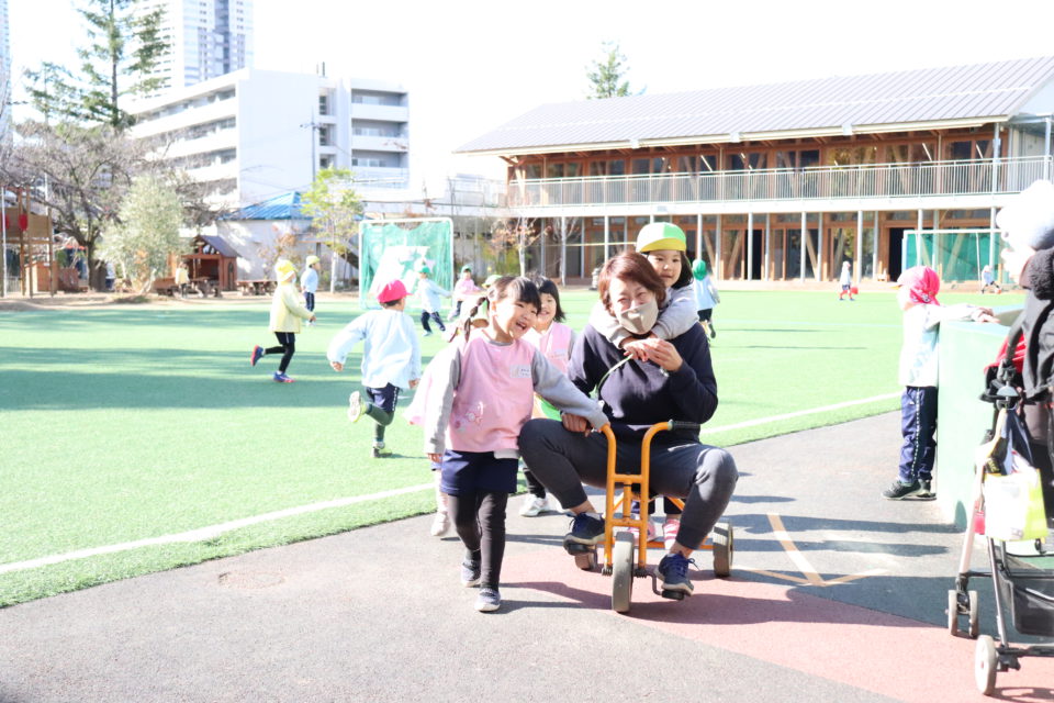 先生と三輪車を楽しむ園児
